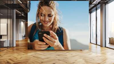 Female mountaineer using phone Wall mural