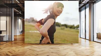 Female runner laughing on field in morning Wall mural