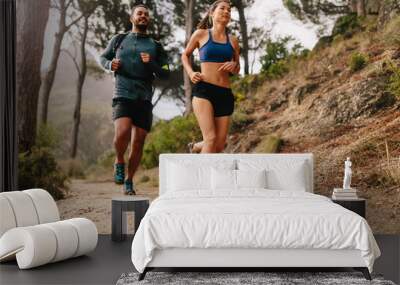 Fit young couple running on mountain trail in morning Wall mural