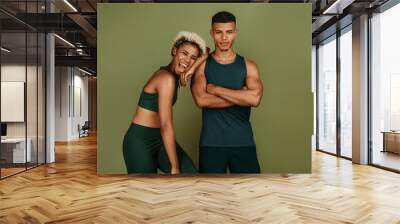 Fitness couple standing together on green background Wall mural