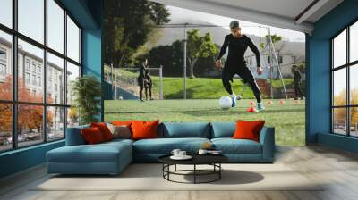 Football player practice dribbling on field Wall mural