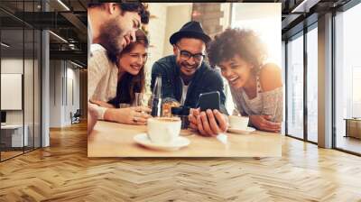 Friends looking at smart phone while sitting in cafe Wall mural