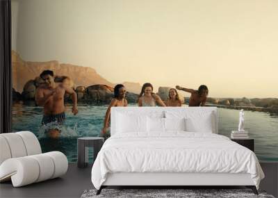 Friends swimming in pool at sunset during summer vacation, enjoying fun and laughter Wall mural