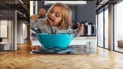 Girl licking chocolate cream while baking Wall mural