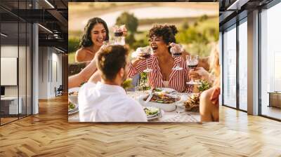 Group of cheerful friends having wine at party Wall mural