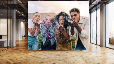 Group of friends blowing confetti during a party Wall mural