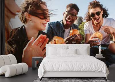 Group of friends eating burger on mountain top Wall mural