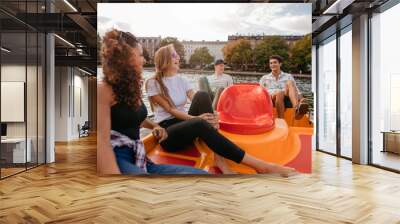 Group of young people sitting on pedal boat in lake Wall mural