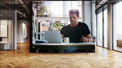 Handsome young businessman working at his desk Wall mural