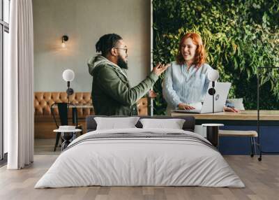 Happy business woman working with her colleague in a cozy cafe Wall mural