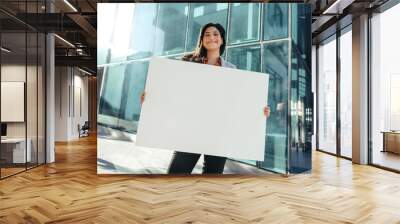 Happy businesswoman holding a white placard outside her workplace Wall mural