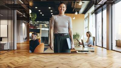 Happy businesswoman standing in a co-working space Wall mural