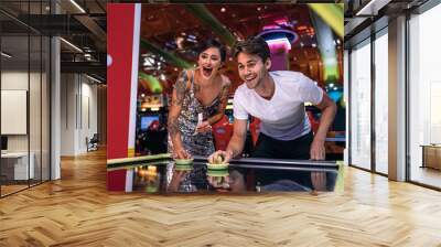 Happy couple playing coin operated air hockey game at a gaming p Wall mural