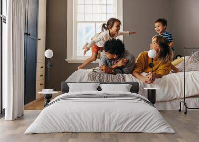 Happy family laughing and having fun together on the bed Wall mural