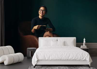 happy female enjoying coffee while sitting on armchair Wall mural