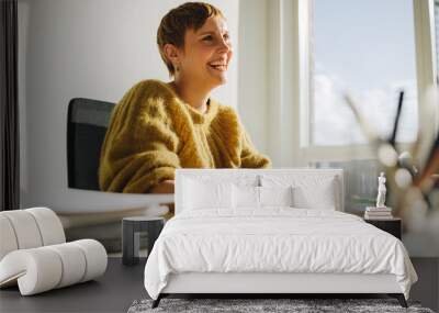 Happy female executive sitting at desk Wall mural