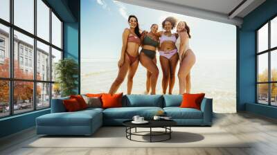 Happy female friends standing on beach water Wall mural