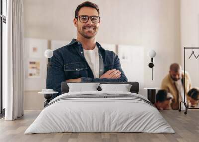 Happy young businessman smiling at the camera with his arms crossed Wall mural