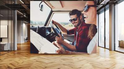 Happy young couple with a map in the car Wall mural