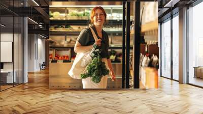 Happy young woman grocery shopping in a supermarket Wall mural