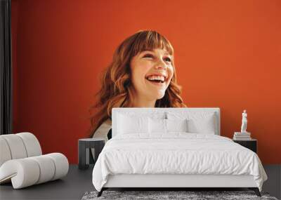 Happy young woman looking away with a smile while standing in a studio Wall mural