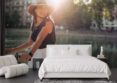 happy young woman riding bicycle by a pond Wall mural