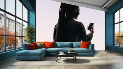 Happy young woman smiling while making a video chat on her smartphone, studio silhouette Wall mural