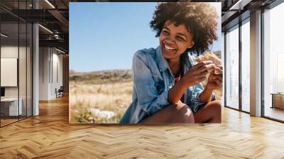 Happy young woman taking break during country hike. Wall mural