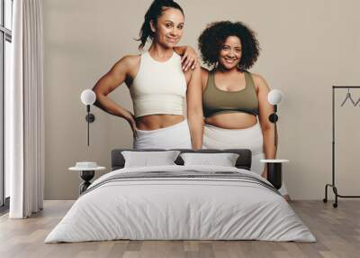 Healthy lifestyle on display: Two young women standing proud in sporty fitness clothes Wall mural