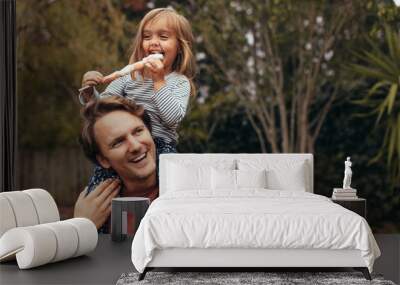 Little girl with her father outdoors holding a candy Wall mural