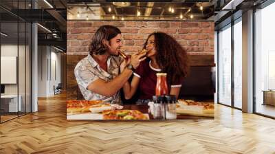 Loving couple feeding each other pizza Wall mural