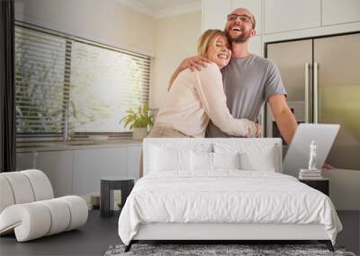 Loving couple with laptop in kitchen at home Wall mural