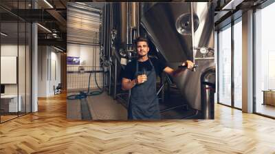 Male brewer standing by tank in brewery Wall mural