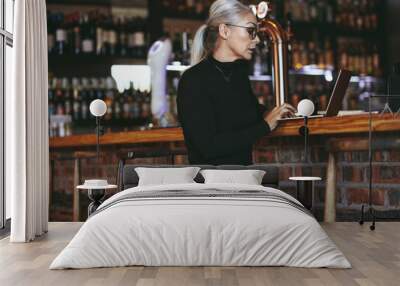 Mature business woman at coffee shop with laptop Wall mural