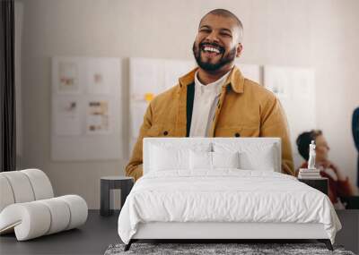 Modern businessman smiling at the camera while holding a smartphone Wall mural