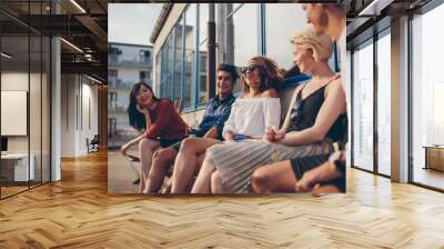 Multiracial group of friends sitting in balcony and smiling Wall mural