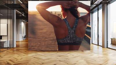 Muscular woman in sports bra at sunset Wall mural