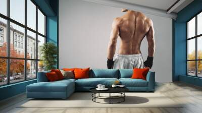 Muscular young male boxer standing on grey background Wall mural