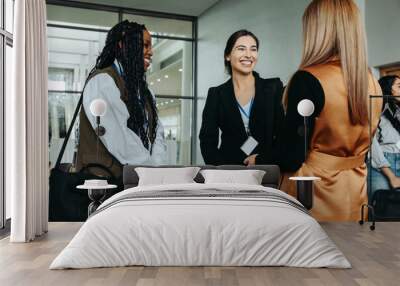 Networking businesswomen smiling and talking at professional conference Wall mural