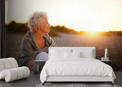 Old woman sitting on the beach looking away at copyspace Wall mural