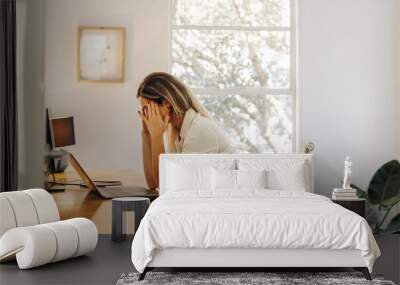 Overworked businesswoman having a headache in her office Wall mural