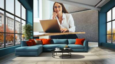 Professional woman smiling at the camera in a modern workspace Wall mural