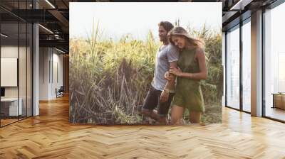 Romantic young couple walking together in countryside Wall mural