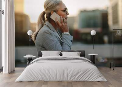 Senior businesswoman talking on cellphone in the city Wall mural