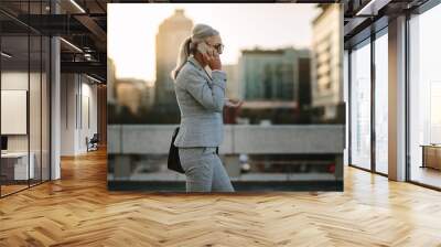 Senior businesswoman using cellphone on city street Wall mural