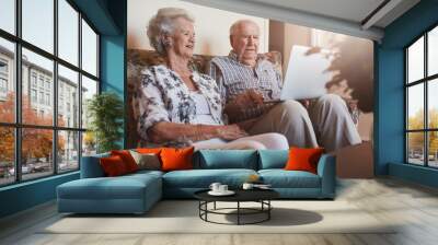 Senior couple sitting together and using laptop Wall mural