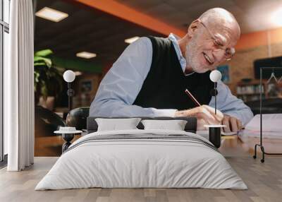 Senior man making notes in classroom Wall mural