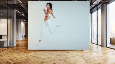 Side view of female athlete running Wall mural