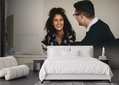 Smiling businesswoman discussing work with colleague in office Wall mural