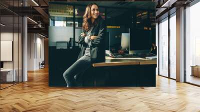 Smiling businesswoman sitting on her desk Wall mural